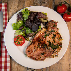 Recipe for grilled pork chop, maple syrup and fresh cilantro marinade, parsley, garlic, served with a salad.