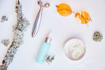 Trendy face care cosmetics background on white background. Serum, mockup cream, massager and sunglasses. Natural eco forest moss. Hyaluronic and moisturizing gel. Dermatology cosmetics. Copy space.