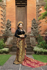 Asian woman wearing Balinese kebaya and woven cloth against temple