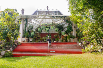 A man stares at the camera from the red stairs in of the great greenhouse of Puerto Vallarta's botanical garden in Mexico