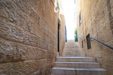 Narrow stone steps in an alley in the Jewish Quarter, with a handle for accessibility for the disabled, in the Old City of Jerusalem, Israel.