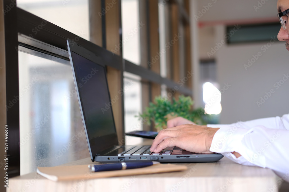 Aufkleber businessman types on a computer keyboard at a wooden desk. banking and strategy development in the o