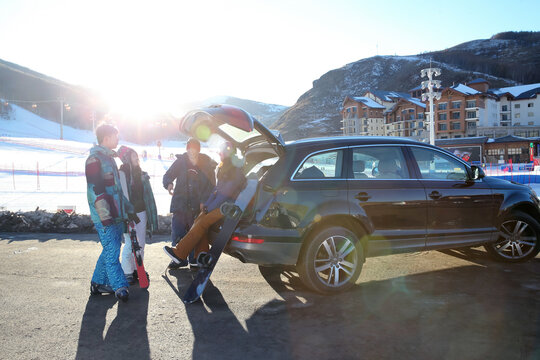 young group friends outdoor skiing sitting on car back