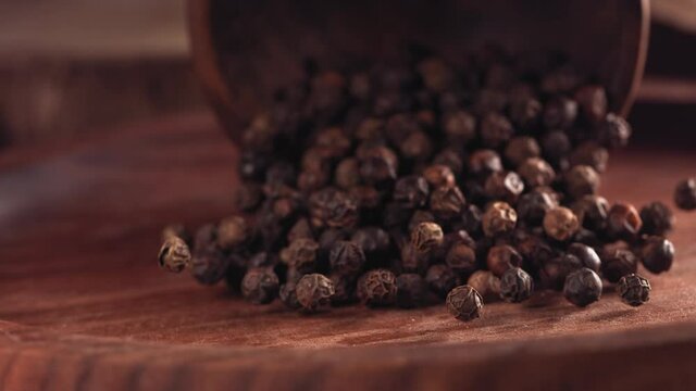 Black pepper falling on a wooden table .Slow motion. Close up