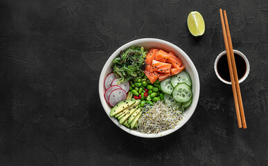 Keto diet poke bowl with salmon, avocado, and edamame beans. over dark background. top view, copy...