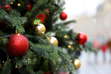 Christmas decorations on a city street. New Year tree with red and golden toy balls on blurred people background