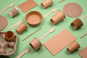 Set of different eco-friendly tableware and kraft paper food packaging on green background. Street...