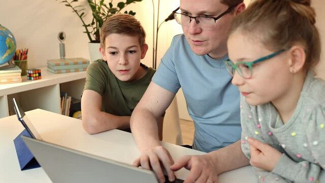 Young father help his children at online lesson with laptop and tablet. 4K 60FPS video - Powered by Adobe