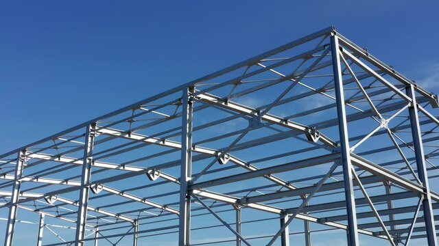 Metal construction - steel frame of unfinished industrial hall. Structure (framework) consisting of iron girders and beams meant to support the roof isolated against blue sky on a sunny day.
