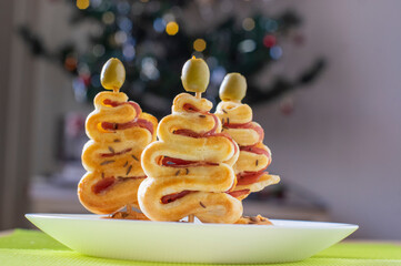 Salty puff pastry bakery with cheese, ham and green olives on the top, group of Christmas tree...