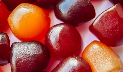 Selective focus.Close-up texture of red, orange and purple multivitamin gummies on white background