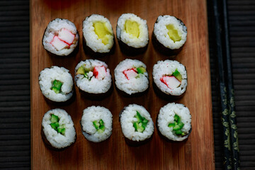 Sushi rolls with vegetable filling over dark bamboo background