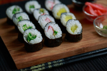 Sushi rolls with vegetable filling over dark bamboo background