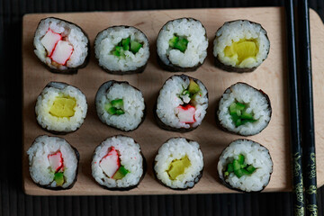 Sushi rolls with vegetable filling over dark bamboo background
