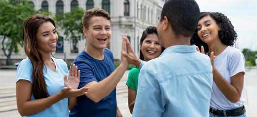 Multiethnic team of young adults give high five to friend