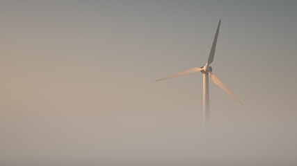 Wind power plant on a foggy morning in the light of the rising sun