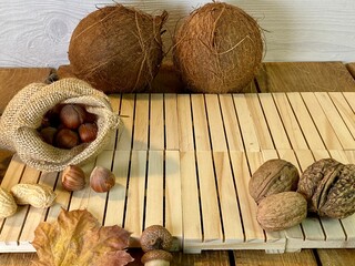 On the oak table are coconut, walnuts and hazelnuts - obrazy, fototapety, plakaty