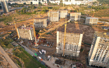 Fototapeta na wymiar Construction site with tower crane on formworks. Crane on construction the building and multi-storey residential homes. Housing renovation concept, aerial view. Built environment.