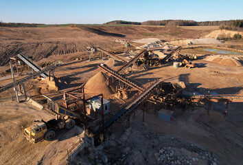 Mining dump truck unloads sand for crushing it into fractions at the crushing plant. Construction sand production near the quarry. Aerial view of an Mining work in open cast © MaxSafaniuk