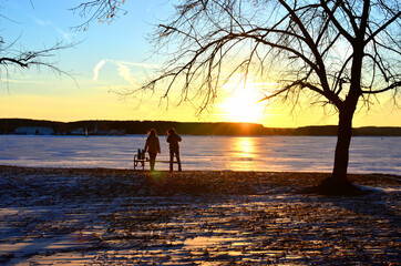 Beautiful winter sunset on a background of a frozen lake. Winter arrives, bodies of water freeze...