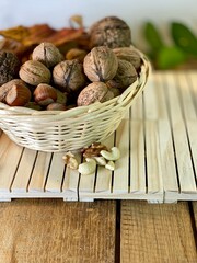 On the oak table there are wooden pallets with walnuts and hazelnuts on them - obrazy, fototapety, plakaty