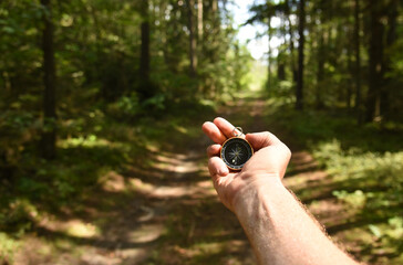 Compass in hand at forest. Tourist compass for orientation on the terrain. Magnetic declination...