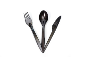 A set of plastic cutlery knife, fork and spoon in black, filmed on a white background