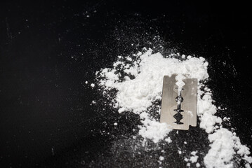 Razor Blade on drug powder on reflection black background.Copy space.