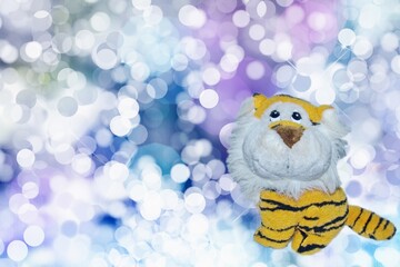 A toy tiger on a sparkling background of New Year`s lights. The tiger is a symbol of the New Year 2022 according to the Eastern calendar. Happy New Year and Merry Christmas!