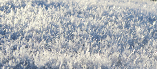 Close-up of snowflakes in the sun on a blurry background. Bright snow, frost sparkles in the sun.