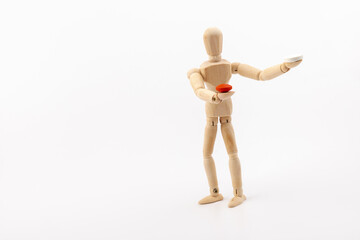A wooden Gestalta doll or mannequin holds red and white pills in its hands on light background. The concept of choice.