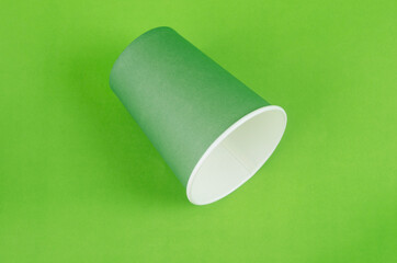 Green color paper drink glass disposable on green background.