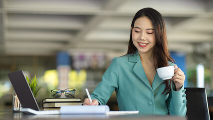 Female boss signing documents while sipping afternoon coffee.