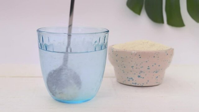 Collagen powder is added to clean water and stirred with a spoon until dissolved. Making a collagen cocktail.
