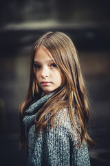 sad teenage girl in a warm sweater on a dark background