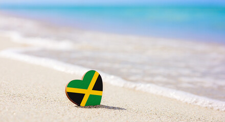Flag of the Jamaica in the shape of a heart on a sandy beach. The concept of the best vacation in...