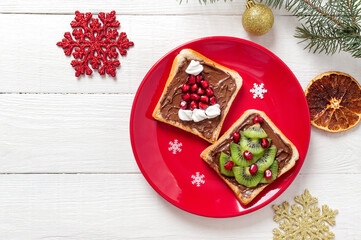 Creative sandwiches in the shape of a Christmas tree and Santa hat, made with fresh fruits and marshmallows. Funny breakfast idea for kids. Top view