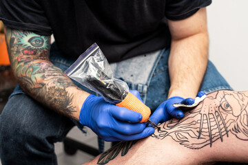 Tattoo artist creates new tiger head tattoo with tattoo skin painting machine on the leg of client...