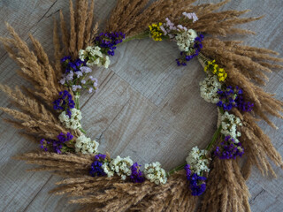 Creative autumn wreath with dried pampas grass and wildflowers on wooden background. space for text. hello fall. happy thanksgiving. Making a beautiful fall wreath for the decor from dried plants.