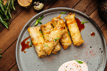 Turkish cigar shaped rolls boreks with sauce on wooden background