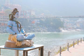 A sculpture of Lord Shiva in front of the Lakshman Jula Bridge in Rishikesh, India. A popular pilgrimage site for Hindus and a tourist destination in India.