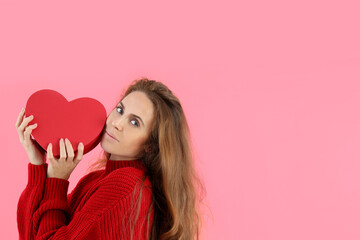 Attractive woman holds heart on pink background