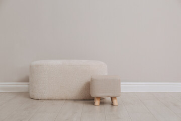 Stylish poufs near beige wall indoors. Space for text