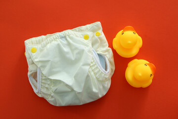 Concept of baby clothes with reusable diapers on orange background