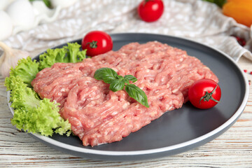 Raw chicken minced meat with basil and vegetables on white wooden table, closeup