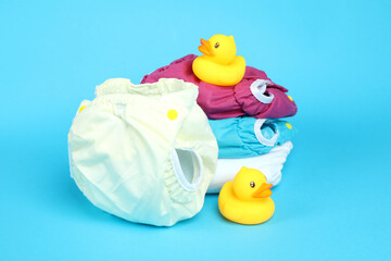 Concept of baby clothes with reusable diapers on blue background