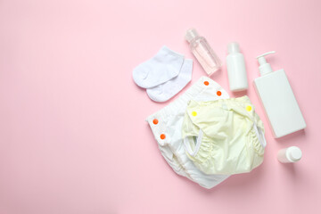 Concept of baby clothes with reusable diapers on pink background