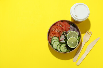 Concept of food delivery with vegetable salad on yellow background
