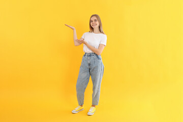 Young attractive girl in jeans on yellow background