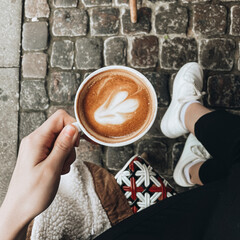 Visiting a French style cafe. Stylish aesthetic photo of coffee from the top. Cup of hot cappuccino and chocolate bun. Cozy atmosphere.